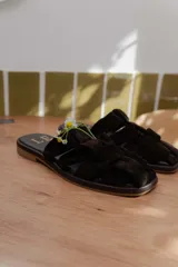 Sandalias tipo mule de cuero color marrón chocolate, con diseño de tiras anchas cruzadas y suela plana.