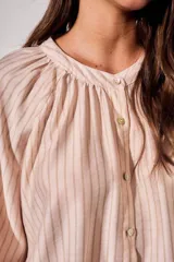 Blusa de manga larga con diseño a rayas verticales, cuello redondo con pequeña abertura frontal abotonada y mangas con puños elásticos.