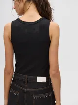 Musculosa básica de diseño crop con textura acanalada y cuello redondo. Presenta un pequeño logo bordado en el centro del pecho y terminaciones en rib.