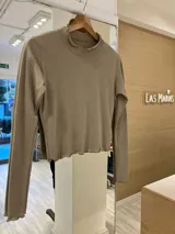 Remera color beige de morley de algodón, de manga larga, con terminaciones fruncidas en cuello y mangas.