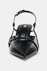 Zapato de tacón fino con acabado en punta, confeccionado en material sintético brillante. Presenta un diseño de tiras cruzadas en el empeine con detalles de hebillas metálicas y una tira trasera ajustable con cierre de hebilla.