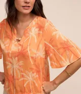 Blusa color naranja con estampado de cocoteros en blanco y rojo, cuello en V con detalle de abalorio de madera y mangas cortas acampanadas.