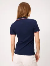 Remera polo azul marino de manga corta, con cuello en V sin botones y ribetes tricolores en el cuello y los puños.
