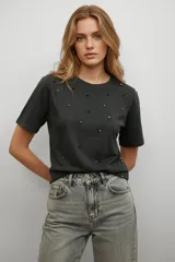Remera de algodón color gris oscuro con cuello redondo y mangas cortas, decorada con pequeñas cuentas esféricas en tonos negro y plateado distribuidas por toda la prenda.