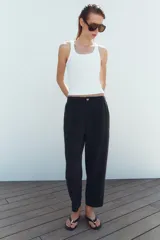 Pantalón de tiro medio color amarillo, con cintura elástica, bolsillos de plastrón en el delantero y pernera holgada que se estrecha hacia el tobillo. Cuenta con cierre frontal de cremallera y botón.