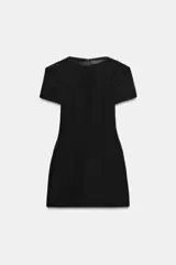 Vestido mini negro con cuello redondo, manga corta con pliegues y costuras marcadas. Cuenta con cierre posterior con cremallera oculta.