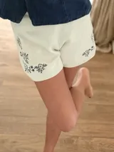Short elastizado color marfil con delicados bordados de flores en tono azul marino en la parte frontal.