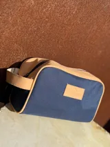 Neceser de lona verde con detalles en cuero color beige y etiqueta con logo de la marca Sierra Mora.