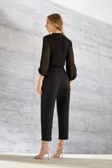 Blusa corta negra de poliéster con mangas largas de gasa abullonadas y cuello redondo. Incluye collar de strass.