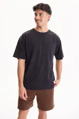 Remera oversize de manga corta raglán, color negro con efecto lavado acid wash, corte semi boxy y detalle de etiqueta lateral en el ruedo.