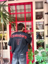 Remera celeste de corte holgado con estampado en rojo en la espalda con el texto "ittaistars", "European Tour by Ittai Stars Company" y el logo de la marca.