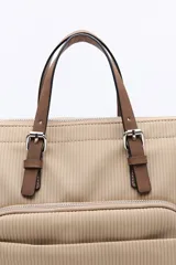 Mochila negra de poliéster texturizado con superficie acanalada. Cuenta con asas superiores marrones, tiras regulables para la espalda, bolsillo frontal con cierre metálico, compartimentos laterales y un interior amplio.