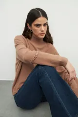 Polera tejida color borgoña, de cuello alto y mangas largas abullonadas con detalle de bordado trenzado en los puños.