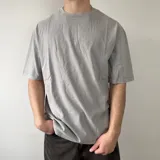 Remera oversize gris con efecto lavado, de manga corta y cuello redondo. Presenta un gran diseño bordado en la espalda con el contorno de una estrella y letras superpuestas.