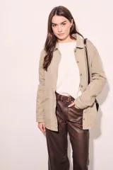 Sobrecamisa color beige de algodón peinado, corte recto, con cuello camisero, cierre frontal con botones y bolsillos de parche en el pecho.