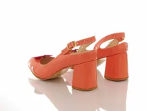 Sandalias de charol color naranja claro, con taco mediano forrado, tira ajustable al talón con hebilla dorada, puntera abierta y detalle de aplique en forma de corazón color fucsia.