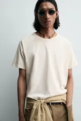 Camiseta relaxed fit color gris oscuro, confeccionada en tejido ligero de algodón con elasticidad. Presenta cuello redondo y manga ranglán corta.