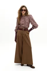 Pantalón culotte color camel con sutiles rayas bordó, de cintura alta y reforzada, con pinzas en la cintura, cierre frontal con gancho y botón interno, y bolsillos laterales. Las piernas son anchas.