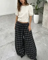 Pantalón de corte amplio y holgado con diseño a cuadros, cintura elástica con cordón ajustable y bajos regulables en las piernas.