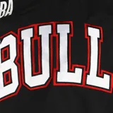 Buzo de entrenamiento NBA de los Chicago Bulls, color negro con detalles en rojo en las mangas y cuello. Presenta el logo de la NBA en el pecho y el nombre del equipo estampado en el frente.