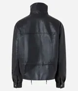 Campera Blue Steel de poliuretano efecto cuero color negro, de corte ligeramente amplio, con cuello alto estructurado, cierre frontal con botones a presión y tapeta superpuesta. Presenta bolsillos delanteros con solapa, cordón regulable en la cintura y mangas largas con puños abotonados.