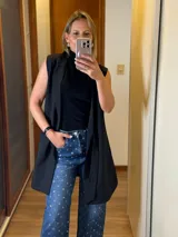 Chaleco vestido color rosado, de corte recto, sin mangas, con cuello tipo blazer y lazo para atar en la cintura.