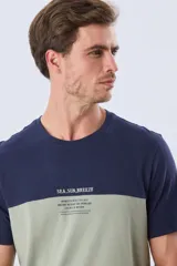 Remera de algodón y poliéster de corte clásico, con diseño en bloques de color negro en la parte superior y gris melange en la inferior. Presenta cuello redondo, mangas cortas y un pequeño estampado tipográfico en el pecho.