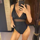 Traje de baño entero negro con escote en V, breteles finos y detalle de transparencia en la cintura.