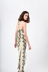 Vestido midi con estampado de piel de serpiente en tonos beige, negro y amarillo. Tiene breteles finos cruzados en la espalda y corte recto.
