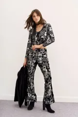 Pantalón de terciopelo negro con estampado floral en plateado, de corte acampanado.