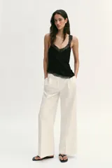 Top confeccionado en hilatura de algodón, con escote en V y tirantes anchos. Presenta detalles de encaje a tono y un diseño de bajo asimétrico.