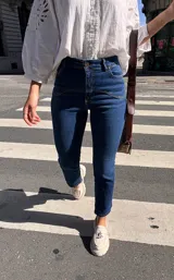 Pantalón de jean azul oscuro, corte recto, tiro alto y detalles de costuras en la parte superior.