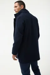 Gabán azul marino con cuello alto y pechera desmontable con cierre.