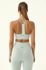 Top deportivo celeste de compresión media, con elástico invisible y tiras delgadas.