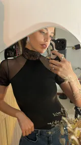 Body negro de terciopelo acanalado con detalles de microtul y encaje, cuello alto y espalda descubierta.