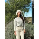 Sweater de punto color blanco marfil, con diseño de trenzas frontales, cuello redondo y mangas largas con puños elásticos acanalados.