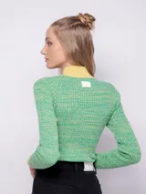 Polera de tejido de punto con textura acanalada, de manga larga y cuello alto. Presenta un diseño bicolor con cuerpo en tono verde jaspeado y detalles en amarillo en cuello y puños.