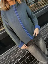 Campera tejida con textura vanizada a rayas verticales en color lila y negro, con cierre frontal y cuello alto.