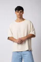 Remera de hombre, color crema, con cuello amplio y corte oversize. El tejido es liviano y texturado, similar al lino.