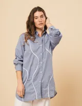 Camisa celeste de algodón con corte oversized, botones frontales a tono y vivos blancos ondulados en el frente.