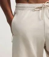 Bermuda deportiva color beige, con cintura elástica, cordón de ajuste, bolsillos con cierre y estampa lateral de lettering.