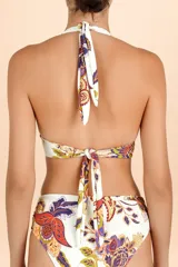 Top de bikini estilo halter con escote profundo y banda ancha bajo el busto. Presenta un diseño estampado con motivos botánicos y paisley en tonos cálidos y púrpura sobre fondo blanco.
