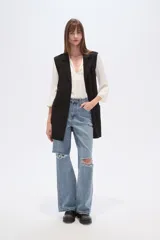 Chaleco largo de corte recto y diseño abierto, con solapas clásicas y bolsillos laterales. Confeccionado en poliéster, presenta una caída fluida y un estilo versátil ideal para superposiciones.