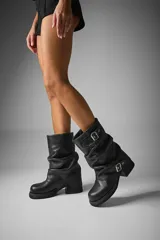 Botas de caña media color negro, confeccionadas en cuero vegano, con hebillas metálicas y suela track.