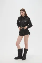 Campera corta de jean negro con costuras en contraste color blanco, cuello camisero, cierre frontal con botones metálicos y bolsillos frontales con solapa.