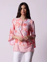 Blusa color salmón con estampado floral blanco, cuello redondo con abertura y mangas 3/4 acampanadas.