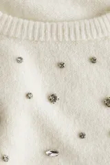 Top de punto fino de manga corta con cuello redondo, decorado con aplicaciones de strass en la parte frontal y acabados acanalados en cuello, puños y bajo.