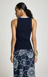 Musculosa azul marino de punto acanalado, con escote redondo ribeteado en celeste y blanco, de corte ajustado y sisas amplias.
