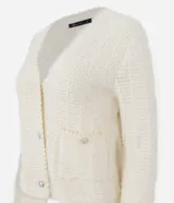 Cardigan de punto con textura de pelitos, cuello en V y cierre frontal con botones metalizados. Presenta mangas largas y dos bolsillos frontales pequeños. Diseño de corte regular.