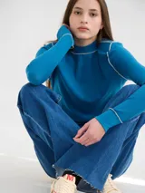 Polera básica de algodón en tejido rib, color turquesa, de manga larga, con hombreras y detalles de pespuntes en color contrastante en las terminaciones y el cuello.